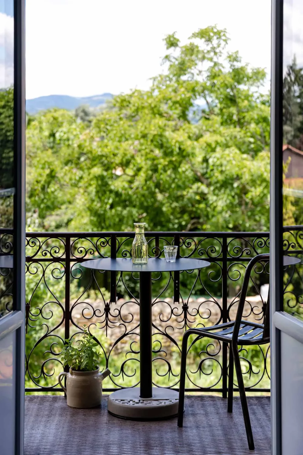 A concrete and aluminum Donut table and a raw metal chair on a country house balcony